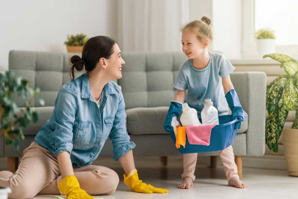 mom and little girl cleaning up vinyl flooring in front of couch in living room